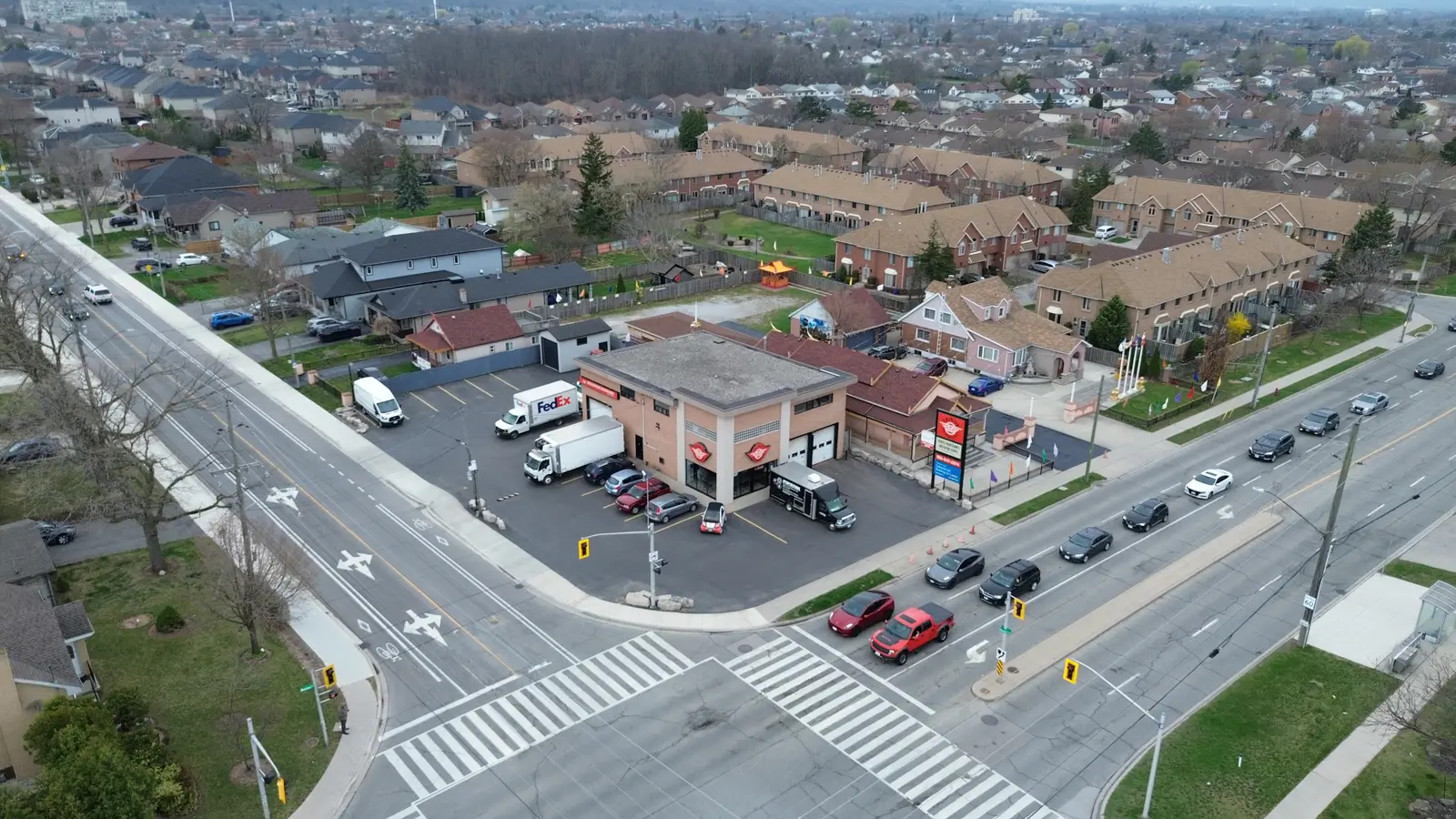 Oblique aerial of the corner property showing a queue of cars at the signal and dense residential streets beyond