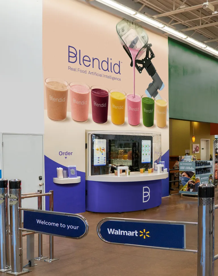 Blendid smoothie kiosk inside a Walmart entrance with a large branded wall