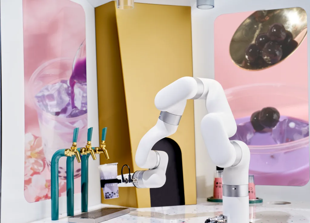 Bobacino robotic boba bar render: white robot arm holding a cup beneath brass taps