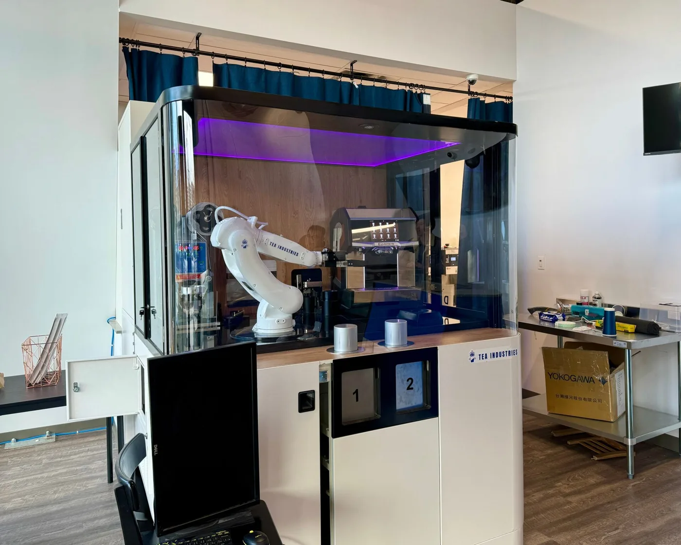 Tea Industries robotic bubble-tea shop interior with a white robot arm in a glass enclosure