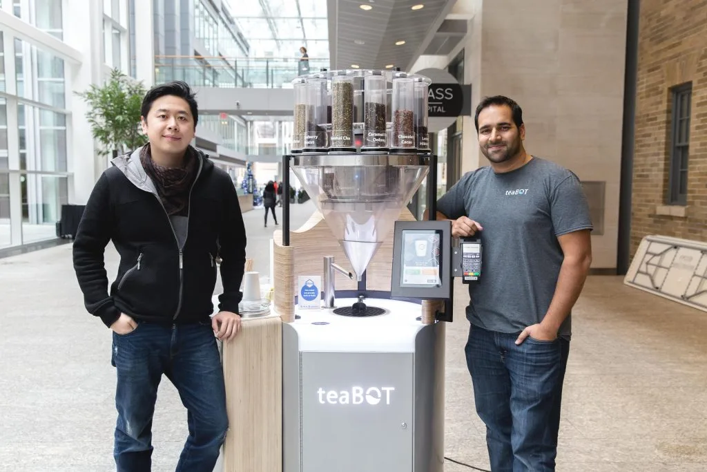 teaBOT founders standing beside their tea kiosk in a Toronto atrium