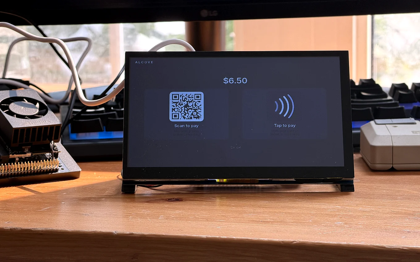 The bench unit's checkout screen seen from the side, the scan-to-pay and tap-to-pay tiles at an angle.