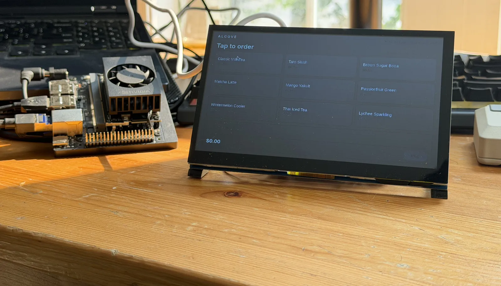 The checkout unit showing a nine-item tap-to-order menu, with the edge computer beside it